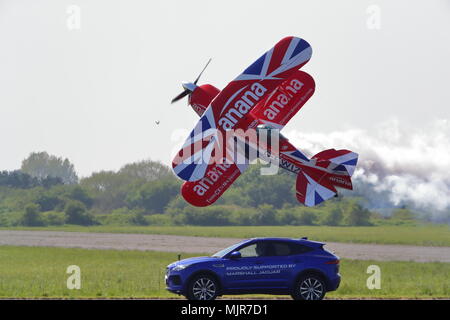 Oxfordshire, UK, 6. Mai 2018. Der waghalsige Pilot Richard Goodwin flog seinen Pitts Special Doppeldecker neben einem Jaguar F-Tempo entlang der Start- und Landebahn in Abingdon. Dies war das erste Mal in dieser Stunt im Vereinigten Königreich gezeigt wurde. Stockfoto