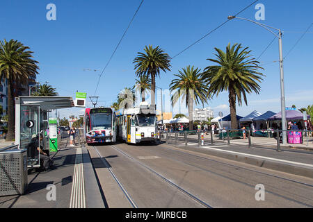 Melbourne, Australien: April 08, 2018: Zwei Straßenbahnen pass auf der Esplanade Straße in St Kilda während eines Sonntag Street Market. Panoramaformat. Stockfoto
