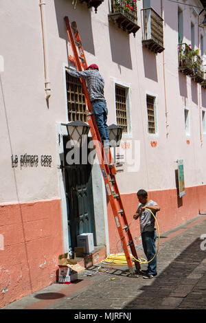 QUITO, ECUADOR - Oktober 27, 2015: Arbeitnehmer mit einer Leiter fix ein Fenster in der Calle La Ronda, typische und bunten kolonialen Street im historischen Stadtteil Stockfoto