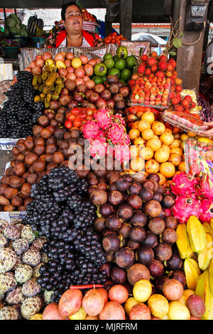 BEDUGUL, Indonesien - 18. MÄRZ 2015: Eine weibliche Verkäufer verkauft eine Reihe von tropischen Früchten in der beliebten Candi Kuning Markt in Bali's Highlands Stockfoto