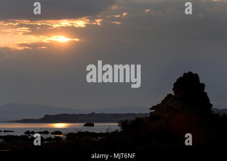 Sun späht aus dem Morgen Wolken über tuffstein Silhouetten am Mono Lake bei Sonnenaufgang. Stockfoto