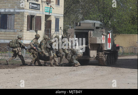 Die Ausübung der Evakuierung Ein verwundeter Soldat Mitglieder von Parachute Regiment transfer in Großbritannien einen "verletzten" Soldaten zu einem Lettischen gepanzerten Ambulanz Stockfoto