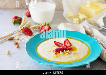 Brei aus Haferflocken mit Muttern und frische Erdbeeren auf Stein oder Schiefer Hintergrund. Das Konzept der Ernährung Gesundheit. Stockfoto
