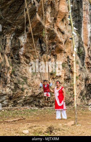 Junge auf Schwingen über und von seiner Mutter Innenraum Nepal half beobachtet werden Stockfoto