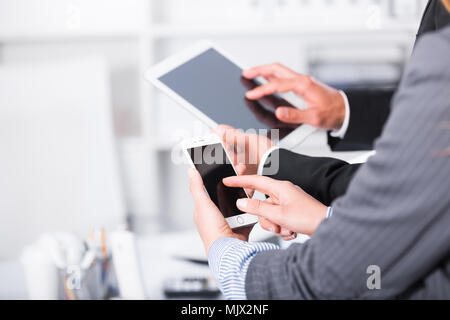 Hände von zwei Geschäftspartnern mit Geräten im Büro für Gestaltung Stockfoto
