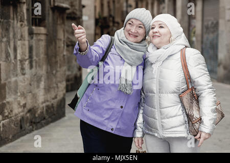 Gerne ältere Frauen genießen Spaziergang durch die Stadt während der melden Sie reisen Stockfoto