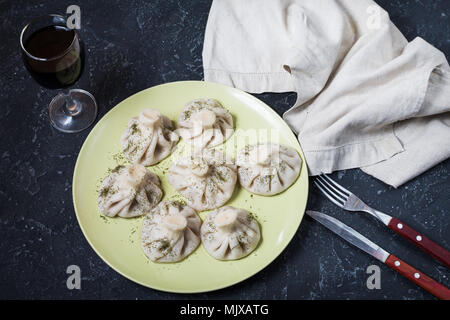 Hausgemachte khinkali Knödel und einem Glas Wein auf dem Stein rustikalen Tisch. Stockfoto