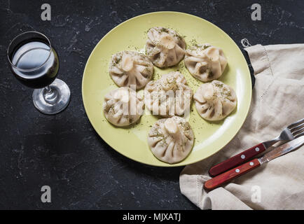 Hausgemachte khinkali Knödel und einem Glas Wein auf dem Stein rustikalen Tisch. Stockfoto