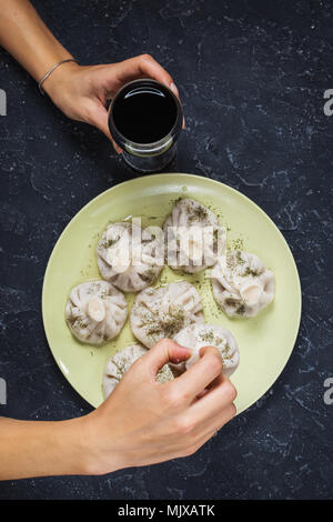 Hausgemachte khinkali Knödel und einem Glas Wein auf dem Stein rustikalen Tisch. Weibliche Hände. Ansicht von oben Stockfoto
