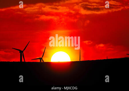 Red Sky weisse Sonne Untergang zwischen fünf Ovenden Moor Windpark Turbinen am Schwarzen Moor Plateau, Benetzt von Ogden, nördlich von Halifax, West Yorkshire, UK Stockfoto