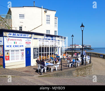 Die Menschen genießen Sie die Frühlingssonne außerhalb ein Café an der Promenade an der North Norfolk resort Cromer, Norfolk, England, Vereinigtes Königreich, Europa. Stockfoto