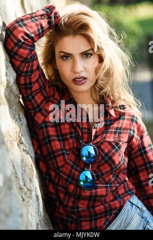 Schöne Frau mit langen blonden Locken. Mädchen in kariertem Hemd. Stockfoto