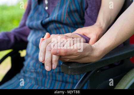 Nahaufnahme Bild der Pflegeperson, die ältere Frau die Hände schütteln, sitzt im Rollstuhl - Parkinson Krankheit Stockfoto