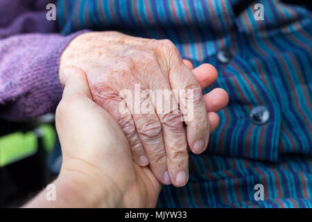 Nahaufnahme Bild der ältere behinderte weibliche Hände mit liebevoller Betreuer Stockfoto