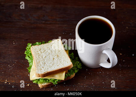 Frühstück mit frischen Käse und Salat Sandwich und Kaffee schwarz in weiß Keramik Becher auf rustikalen Holzmöbeln Hintergrund, Nahaufnahme, selektiven Fokus. B Stockfoto