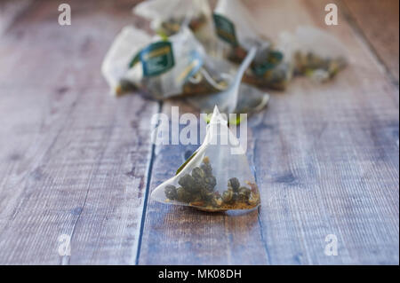 Twinings Jasmin Tee Perlen mit Rosenblättern in dreieckigen Teebeutel auf einer hölzernen Tischplatte Stockfoto