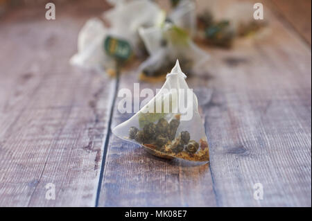 Twinings Jasmin Tee Perlen mit Rosenblättern in dreieckigen Teebeutel auf einer hölzernen Tischplatte Stockfoto