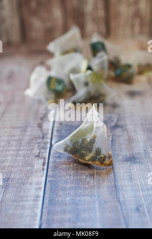 Twinings Jasmin Tee Perlen mit Rosenblättern in dreieckigen Teebeutel auf einer hölzernen Tischplatte Stockfoto