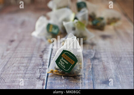 Twinings Jasmin Tee Perlen mit Rosenblättern in dreieckigen Teebeutel auf einer hölzernen Tischplatte Stockfoto