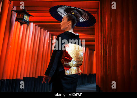 Asiatische Frau in der traditionellen japanischen Kimonos an Fushimi Inari Schrein in Kyoto, Japan Stockfoto