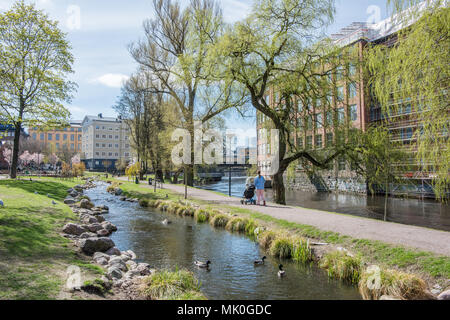 Nicht erkennbare Menschen gehen in Waterfront Park Strömparken entlang Fluss Motala in Norrköping im Frühjahr in Schweden Stockfoto