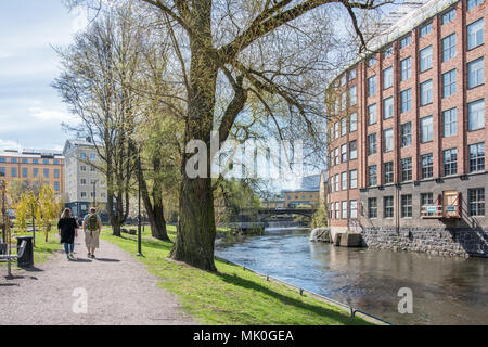 Nicht erkennbare Menschen gehen in Waterfront Park Strömparken entlang Fluss Motala in Norrköping im Frühjahr in Schweden Stockfoto