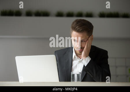 Frustriert Geschäftsmann news Lesen über die Krise auf Laptop Stockfoto