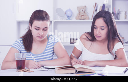Zwei Mädchen Mitschüler sitzen am Tisch zu Hause und gemeinsam Hausaufgaben Stockfoto