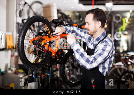 Lächelnden jungen Mann bei der Arbeit auf dem Master Mechaniker Montage Fahrrad Ausrüstung Stockfoto