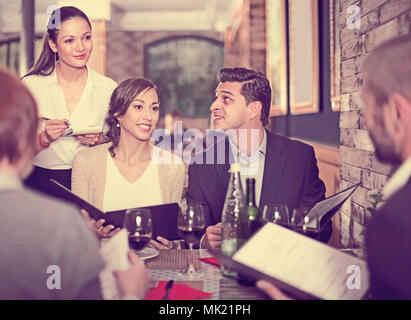 Mitarbeiter Kellnerin weibliche, um von positiven Besucher im Restaurant Stockfoto