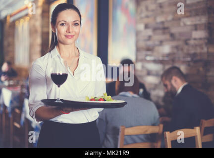 Professionelle happy Kellnerin holding Serviertablett für Gäste Stockfoto