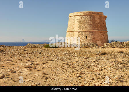 Panoramablick auf das 18. Jahrhundert Wehrturm des Sa Gavina mit Es Vedrá Insel in der Ferne in Formentera (Balearen, Spanien) Stockfoto