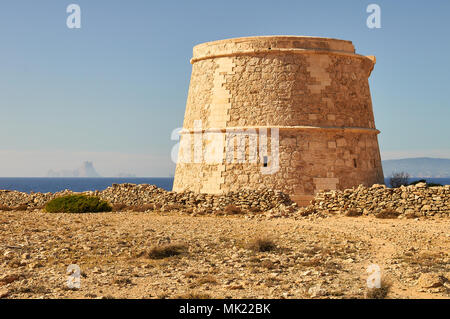 Panoramablick auf das 18. Jahrhundert Wehrturm des Sa Gavina mit Es Vedrá Insel in der Ferne in Formentera (Balearen, Spanien) Stockfoto