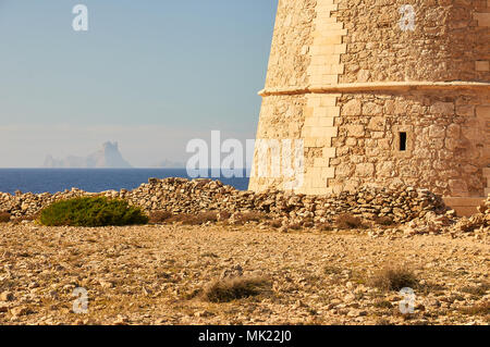 Panoramablick auf das 18. Jahrhundert Wehrturm des Sa Gavina mit Es Vedrá Insel in der Ferne in Formentera (Balearen, Spanien) Stockfoto