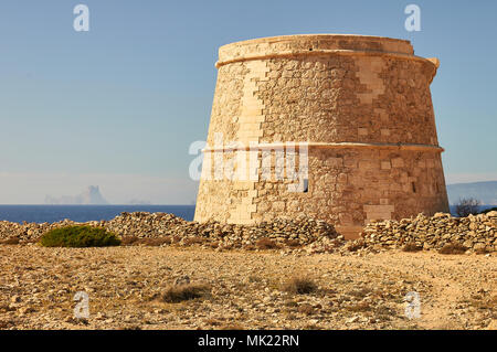 Panoramablick auf das 18. Jahrhundert Wehrturm des Sa Gavina mit Es Vedrá Insel in der Ferne in Formentera (Balearen, Spanien) Stockfoto