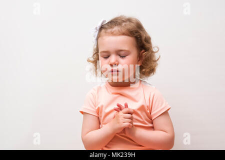 Portrait von kleinen niedlichen Mädchen, betet oder Träume auf weißem Hintergrund Stockfoto