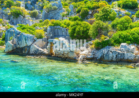 Eingerückt an der felsigen Küste der Insel Kekova mit gut erhaltenen Ruinen des antiken versunkene Stadt unter den grünen Büschen, Türkei. Stockfoto