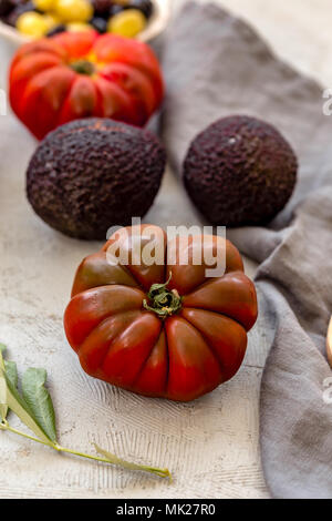 Vertikaler Tomate auf Beton Tischplatte mit Avocado und anderen Tomate unscharf. Stockfoto
