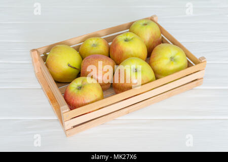 Holzkiste Karton voll Frische Äpfel auf weißen Tisch isoliert. Stockfoto