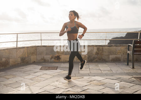 Eine hübsche Brünette, die auf der Promenade in Strumpfhosen und ein Tank Top mit ihren Haaren gebunden zurück Stockfoto