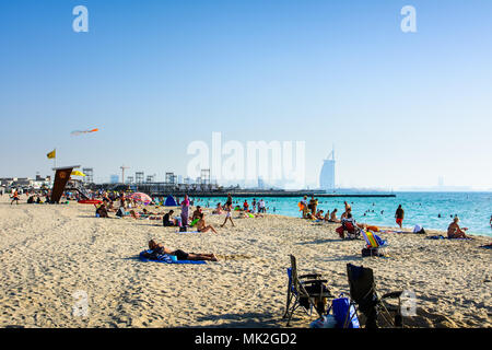 Dubai, Vereinigte Arabische Emirate, 20. April 2018: Kite Beach in Dubai mit vielen Besuchern und Burj Al Arab Hotel im Hintergrund an einem sonnigen Tag Stockfoto