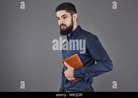 Portrait von toothy gut aussehender bärtiger Mann mit Buch auf Händen Stockfoto