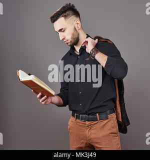 Portrait von toothy gut aussehender bärtiger Mann mit Buch auf Händen Stockfoto
