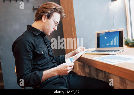 Geschäftsmann mit Laptop mit Tablet- und Stifteigenschaften auf hölzernen Tisch im Café bei einer Tasse Kaffee. Ein Unternehmer, der sein Unternehmen verwaltet remote die als Freelancer. Stockfoto