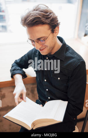 Fröhliche Geschäftsmann in weißem Hemd sitzt im Cafe gekleidet und ein Buch lesen Stockfoto
