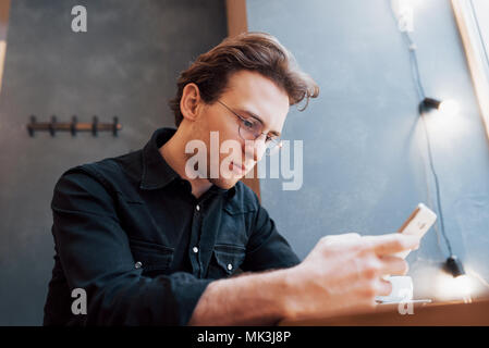 In der Nähe von Mann erhielt gute Nachrichten auf Smart Phone, Mann im Cafe ausruhen und texting neue E-Mails, unscharfen Hintergrund, flacher DOF Stockfoto