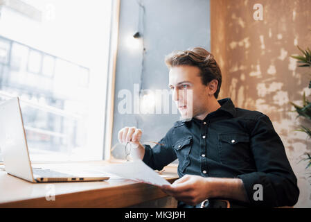 Entspannt Young Professional Surfen im Internet auf seinem Laptop in einem Café Stockfoto