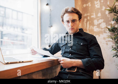 Entspannt Young Professional Surfen im Internet auf seinem Laptop in einem Café Stockfoto