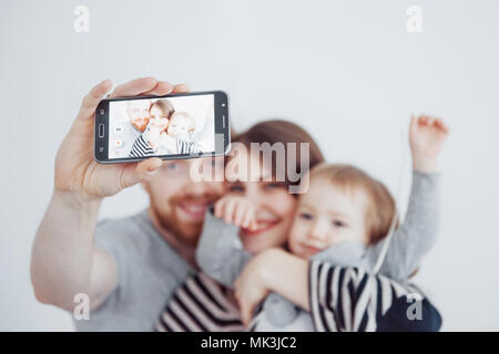 Familie, Feiertage, Technik und Mensch - lächelnd, Mutter, Vater und kleine Mädchen, selfie mit Kamera auf weißem Hintergrund Stockfoto