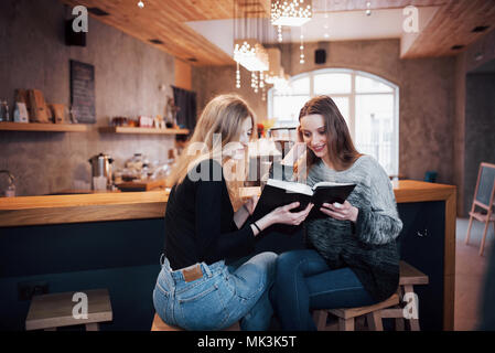 Zwei Mädchen, die in der Lesung buchen Sie während der Pause im Cafe absorbiert. Süße schöne junge Frauen lesen und Kaffee trinken Stockfoto